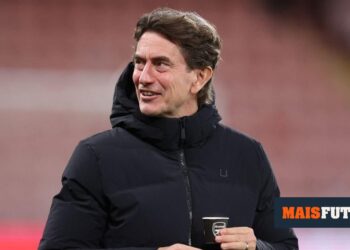 Unusual: Tottenham coach drinks coffee from a cup with the Arsenal symbol